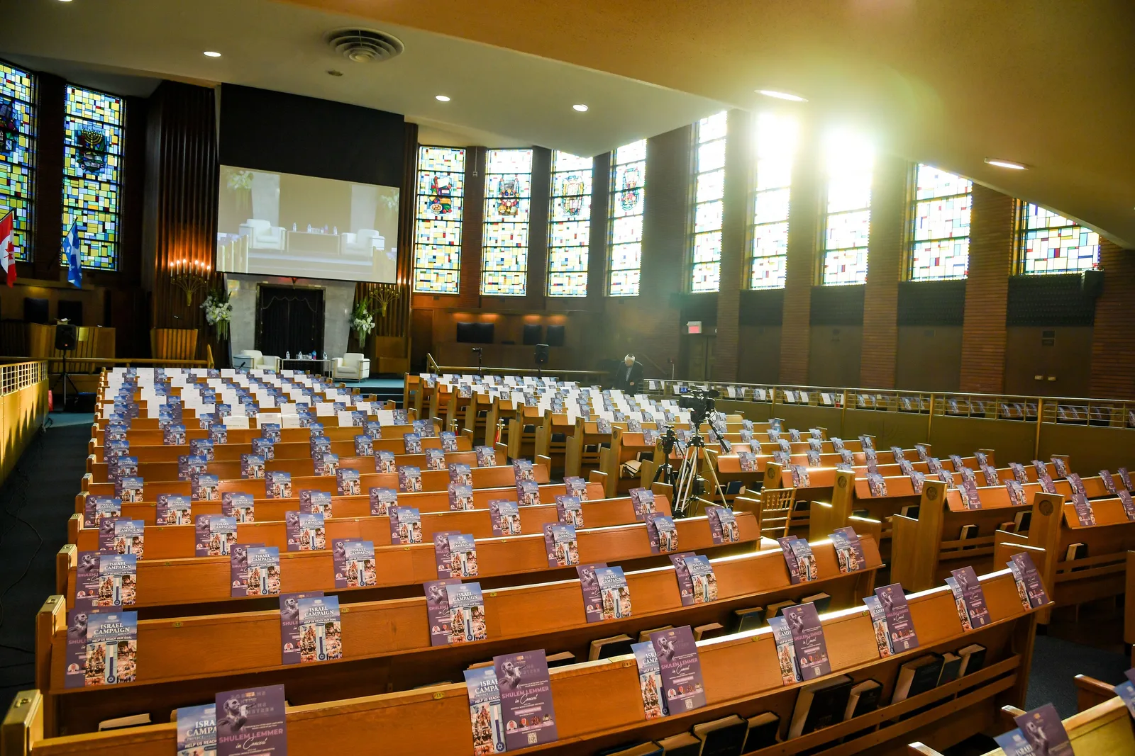 Late sun streaming through the sanctuary’s tall stained-glass windows over rows of wooden pews