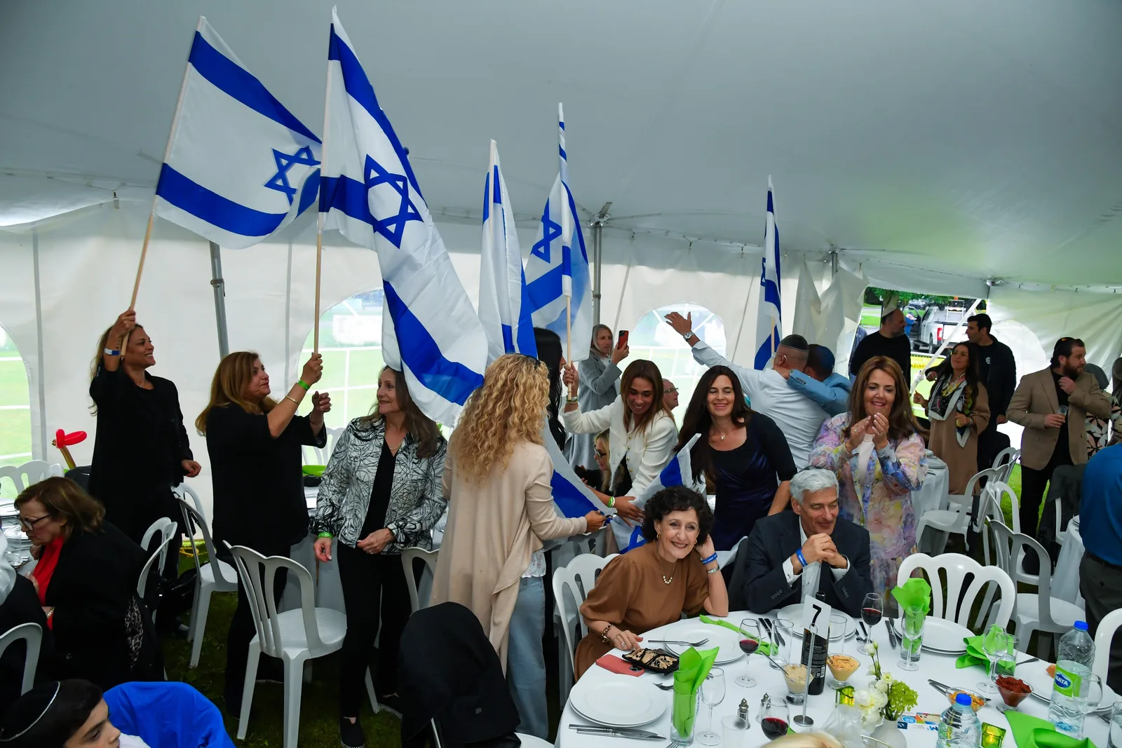Guests dancing and waving Israeli flags under the big tent